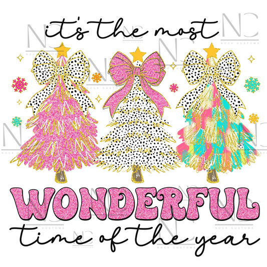 Bright and festive Christmas tree trio design with pink, polka dots, and multicolored trees reading 'It's the most wonderful time of the year' on various t-shirt colors.