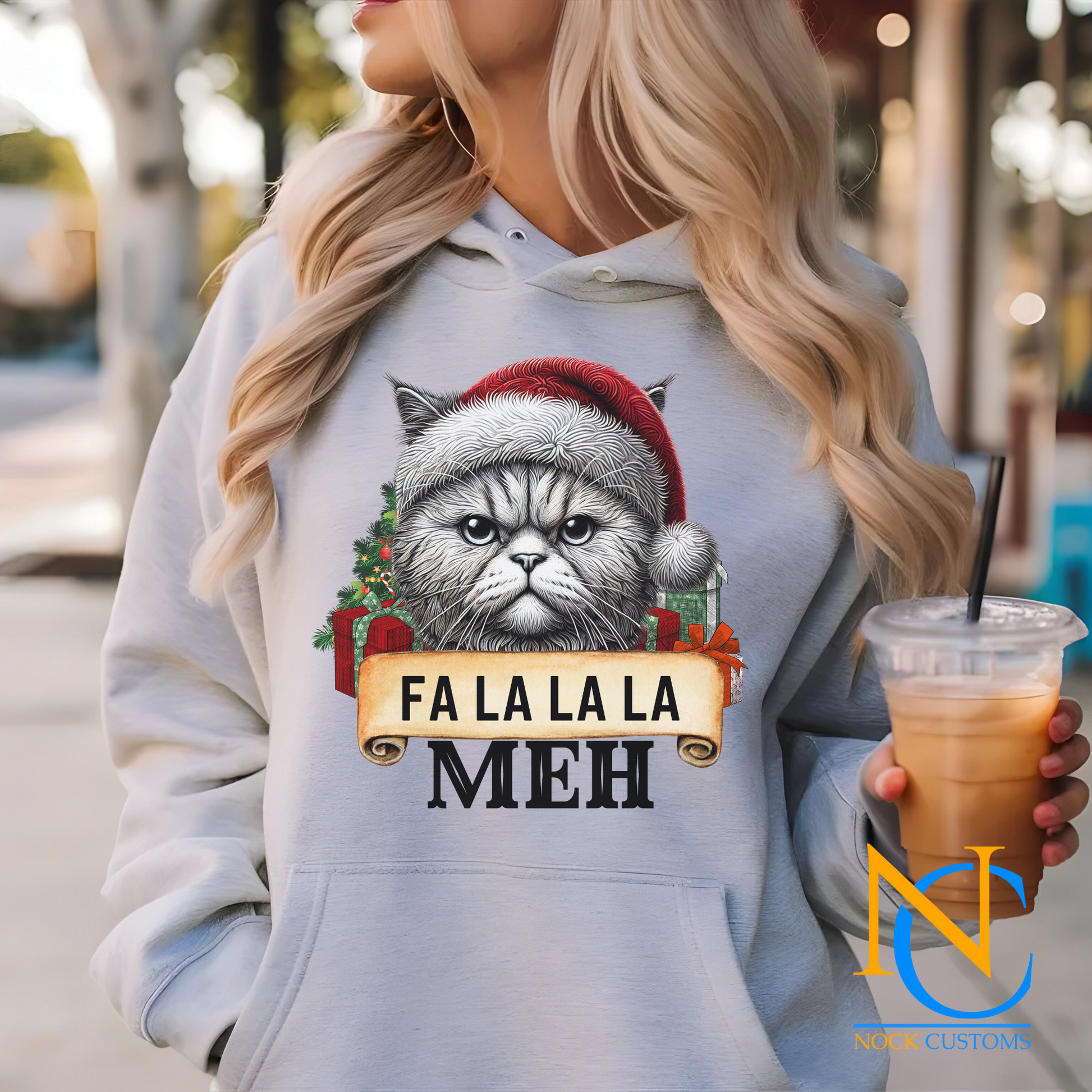 Close-up of a cat-themed holiday design on a hoodie, featuring 'Fa La La La Meh' in festive lettering.