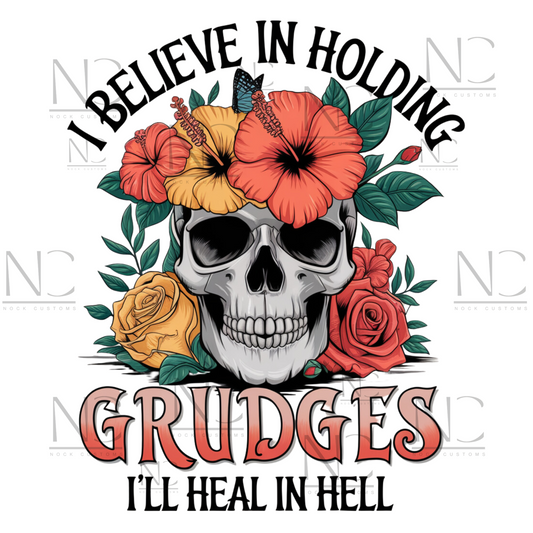 A striking design featuring a skull adorned with vibrant hibiscus flowers, roses, and greenery, with the text 'I Believe in Holding Grudges, I'll Heal in Hell.' Perfect for direct-to-film (DTF) transfers with a bold and sarcastic edge.