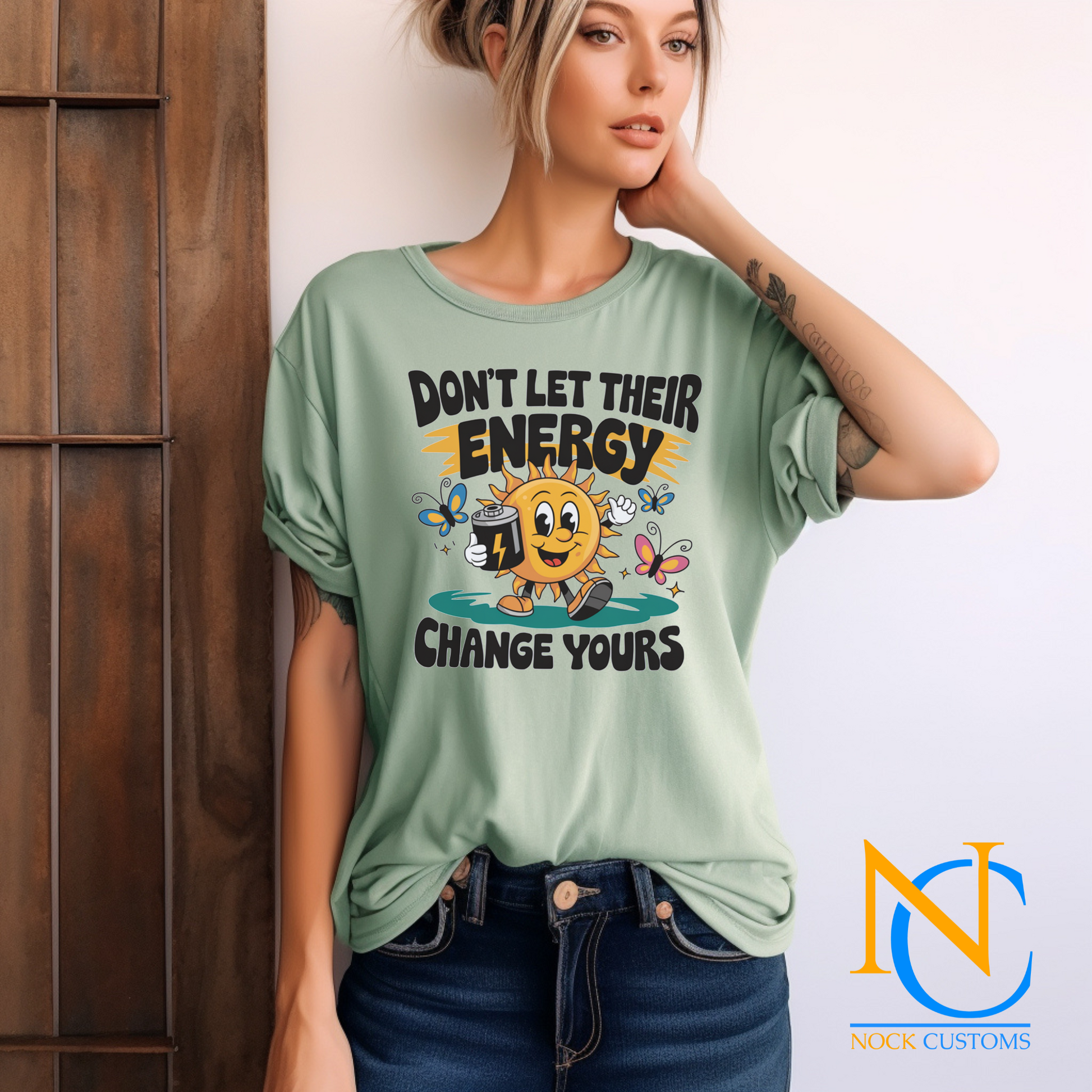 A cheerful design featuring a smiling sun holding a battery, surrounded by colorful butterflies and the text 'Don't Let Their Energy Change Yours.' Perfect for direct-to-film (DTF) transfers with a motivational and uplifting vibe.