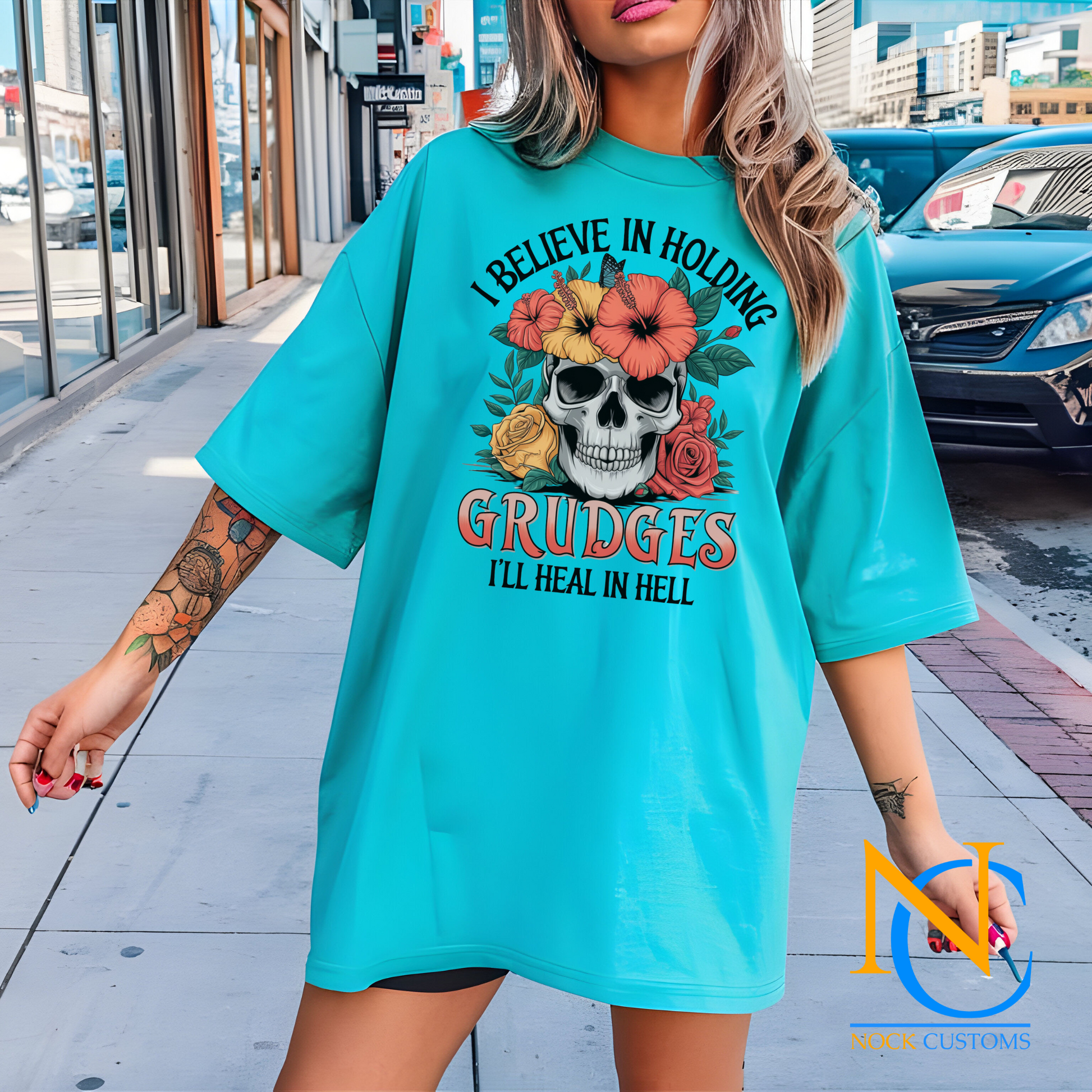 A striking design featuring a skull adorned with vibrant hibiscus flowers, roses, and greenery, with the text 'I Believe in Holding Grudges, I'll Heal in Hell.' Perfect for direct-to-film (DTF) transfers with a bold and sarcastic edge.